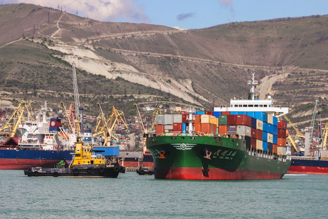A container ship maneuvers in a busy industrial harbor.